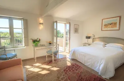 a bedroom with a white bed and a desk and window at Le Jas de Gordes in Gordes