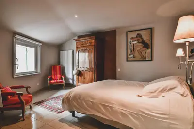 a bedroom with a bed and a red chair at Escapade en Provence in LʼIsle-sur-la-Sorgue
