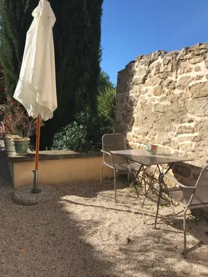 an umbrella sitting next to a table and chairs at Gîte Crillon - Mas Les Fleurs d'Hilaire in Monteux