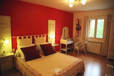 a bedroom with a bed with red walls and a desk at Mas de la Sauline in La Roque-dʼAnthéron