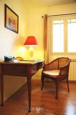 a desk with a lamp and a chair next to a window at Mas de la Sauline in La Roque-dʼAnthéron