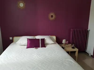 a bedroom with a white bed with purple walls at Location maison Monteux in Monteux
