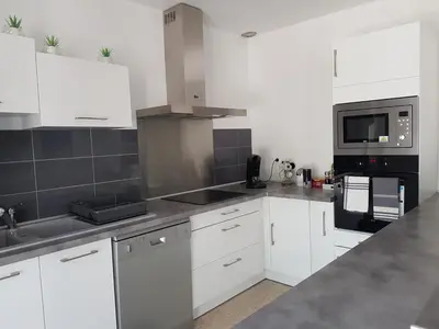 a kitchen with white cabinets and a black microwave at Location maison Monteux in Monteux