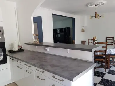 a kitchen with white cabinets and a black counter top at Location maison Monteux in Monteux