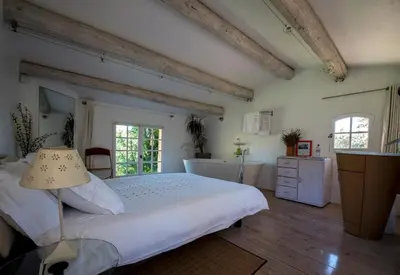 a bedroom with a large white bed and two windows at La Ferme in Saint-Marc-Jaumegarde