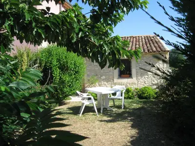 a white table and chairs in a yard with a building at La Bastide des Raisins in Apt