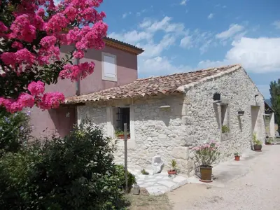a stone house with pink flowers in front of it at La Bastide des Raisins in Apt