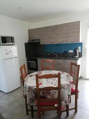 a kitchen with a table and chairs and a white refrigerator at Sophie et Jamiel in Eyragues