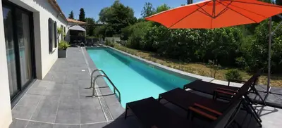 a swimming pool with a red umbrella and chairs at charming family house with pool located at L'isle sur la sorgue - sleeps 8 in LʼIsle-sur-la-Sorgue