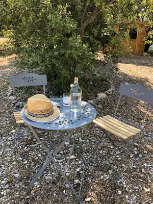 a picnic table with a hat and two chairs at La Maison Bougnette in Flassan