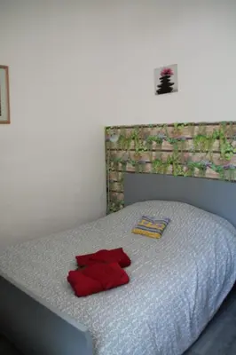 a bed with red pillows and a laptop on it at Au bonheur de LILI in Fontaine-de-Vaucluse