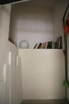 a shelf in a room with books and a light at Au bonheur de LILI in Fontaine-de-Vaucluse