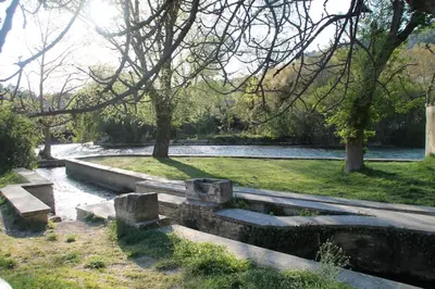 a park with benches and a river with trees at Au bonheur de LILI in Fontaine-de-Vaucluse