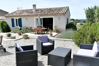 a patio with chairs and a table and a house at Le Mas des Genets in Saint-Rémy-de-Provence