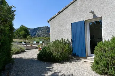 a barn with a blue door in a yard at Le Mas des Genets in Saint-Rémy-de-Provence