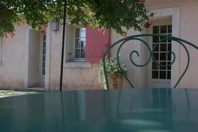a glass table in front of a pink building at gîte Mas Antinea in Mazan
