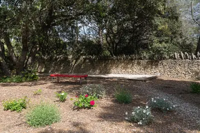 a red bench in front of a stone wall at Maison atypique en Provence chez Brigitte in LʼIsle-sur-la-Sorgue