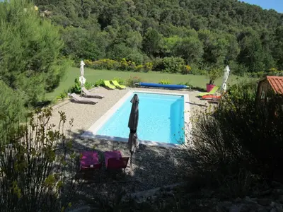 a swimming pool with a umbrella and chairs and a pool at Résidence de gîtes La Sidoine du Mont-Ventoux in Crillon-le-Brave