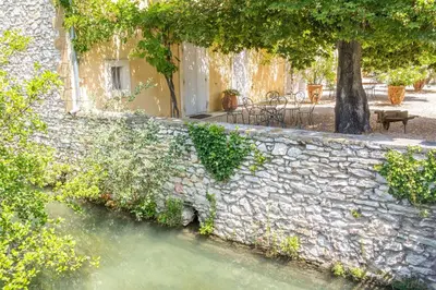 a stone wall next to a body of water at Domaine de Blanche Fleur in Châteauneuf-de-Gadagne