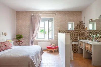 a bedroom with a bed and a sink and a brick wall at Domaine de Blanche Fleur in Châteauneuf-de-Gadagne