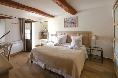 a bedroom with a large bed with white sheets and pillows at LA FERME DE LA HUPPE in Gordes
