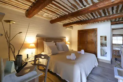 a bedroom with a bed and a desk with a laptop at LA FERME DE LA HUPPE in Gordes