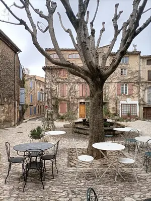 a courtyard with tables and chairs and a tree at Entre Terre et Ciel. in Saignon