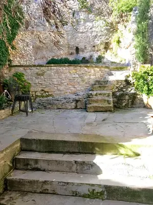 a stone wall with stairs and a bench in a yard at la bonbonniere - Townhouse Saint-Saturnin-lès-Apt in Saint-Saturnin-les-Apt