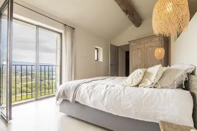 a bedroom with a large bed and a large window at Maison Ventoux in Crillon-le-Brave