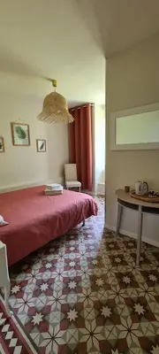 a bedroom with a red bed and a table at La Bastide des Arts in Saumane-de-Vaucluse