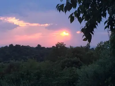 a sunset in the sky over a forest at Gîte du Jardin des Espuys in Venasque