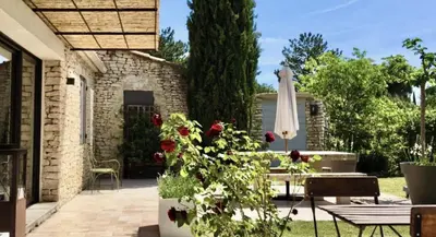 a patio with a table and an umbrella and roses at Le Mas les Pléiades - Private pool - Gordes in Gordes