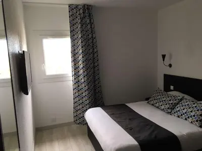 a small bedroom with a bed and a window at Brit Hotel Salon de Provence in Salon-de-Provence