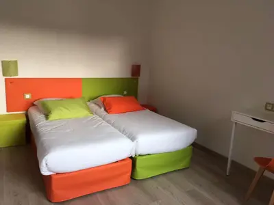 a bedroom with two beds with different colored sheets at Brit Hotel Salon de Provence in Salon-de-Provence