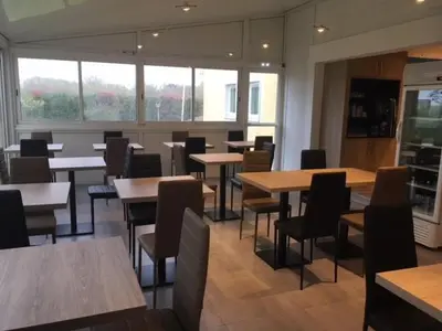 a dining room with tables and chairs and windows at Brit Hotel Salon de Provence in Salon-de-Provence
