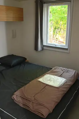 a bed sitting in a room with a window at Camping le Colorado in Rustrel