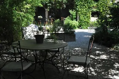 a table and chairs in a garden with trees at La demeure in Eyguières