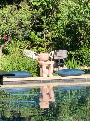 a stone statue sitting next to a swimming pool at La demeure in Eyguières