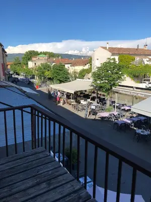 a balcony with a view of a town with tables and chairs at 13 QUAI JEAN JAURES in LʼIsle-sur-la-Sorgue