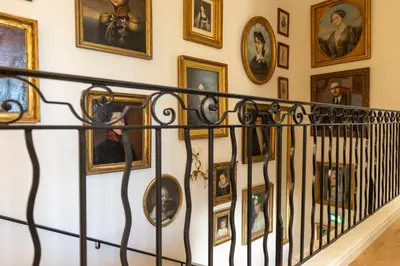 a hallway with portraits on the wall and a railing at Villa Saint-Ange in Aix-en-Provence