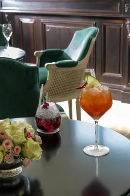 a table with a drink and flowers on it at Villa Saint-Ange in Aix-en-Provence