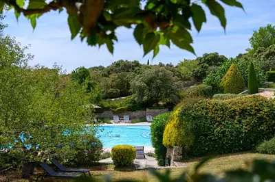 a swimming pool in a garden with bushes and trees at Hotel Les Bories & Spa in Gordes