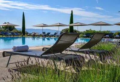a group of chairs and umbrellas next to a pool at Hotel Les Bories & Spa in Gordes