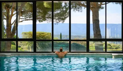 a person sitting in a swimming pool in a house at Hotel Les Bories & Spa in Gordes