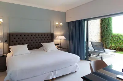 a bedroom with a large white bed and a balcony at Hotel Les Bories & Spa in Gordes