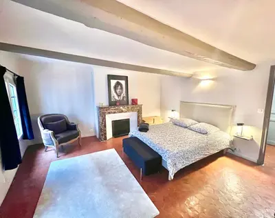a bedroom with a bed and a chair and a fireplace at Maison Alberta in Aix-en-Provence