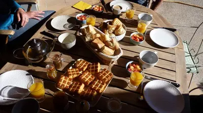 a wooden table topped with waffles and baskets of food at Le mas de la diligence in Mirabeau