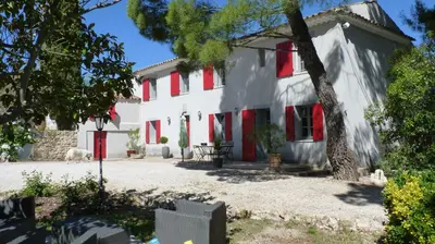 a white house with red shutters and a tree at Le mas de la diligence in Mirabeau
