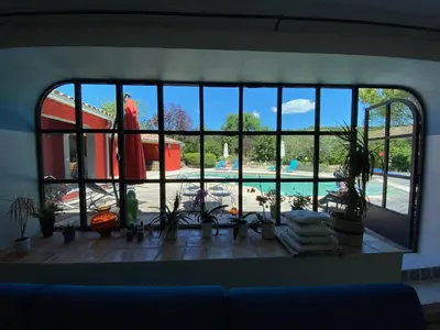 a room with a large window looking out at a pool at Le mas de la diligence in Mirabeau