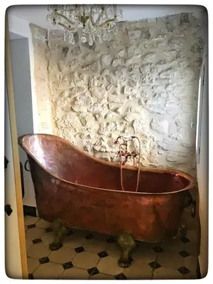 an old copper tub in front of a stone wall at La Providence in Apt